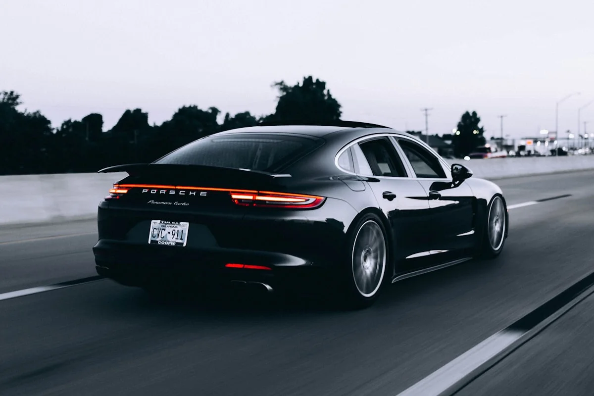 Executive luxury saloon sedan parked in profile with evening city lights.